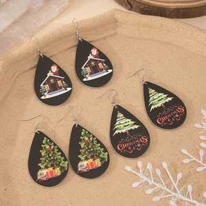 Three pairs of wooden teardrop earrings with Christmas prints in a ceramic tray