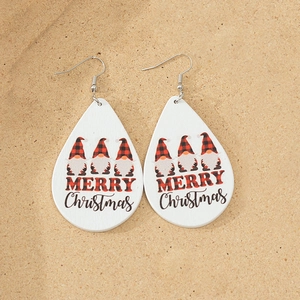 Close-up of wooden teardrop earrings with Christmas gnomes and Merry Christmas text