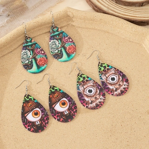 Drie paar acryl druppeloorbellen met Halloween-patronen zoals piratenoog en rozenmotief