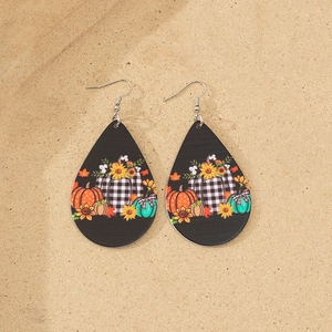 Close-up of teardrop acrylic earrings with autumn pumpkins and sunflower prints