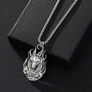 Close-up of vintage Anubis relief pendant with a silver box chain on dark background