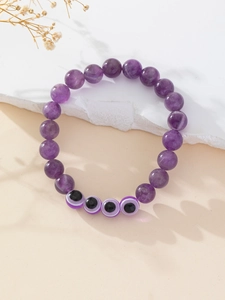 Detail of purple natural stone beaded bracelet with Turkish evil eye charms and quartz
