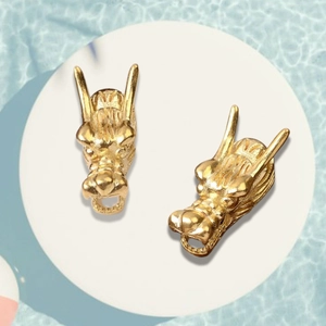 Macro shot of gold-plated dragon head pendants with intricate scale texture and detail