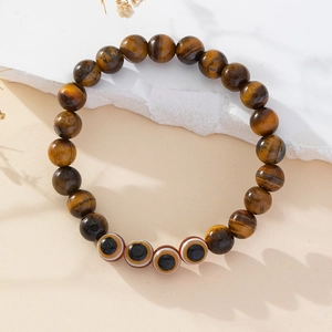 Detailed close-up of tiger eye stone beads and evil eye charm on handmade bracelet