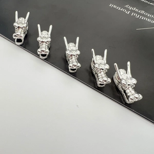 Detailed macro view of five polished silver alloy dragon head charms for jewelry making