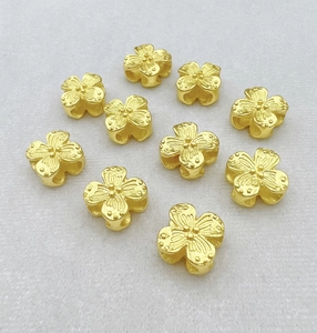 Macro shot of 10 golden clover hollow charms with textured surface for DIY jewelry making