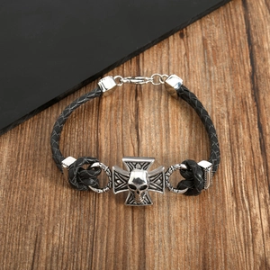 Close-up of woven leather bracelet featuring retro silver skull and cross metal charms