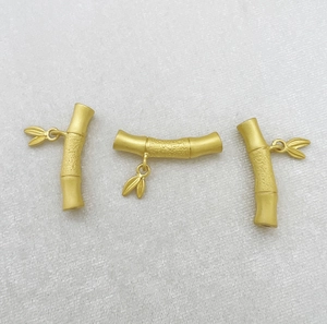 Detailed macro view of matte gold bamboo shaped jewelry components with small leaf pendants