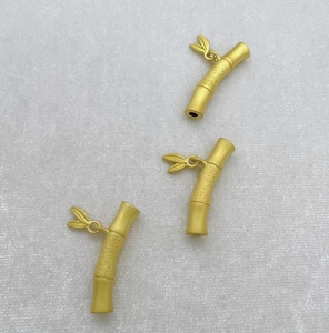 Macro view of matte gold bamboo-shaped jewelry connectors with delicate leaf charms