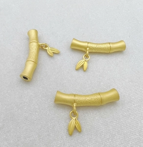 Detailed macro view of matte gold bamboo shaped jewelry connectors with small leaf charms