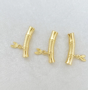 Detailed macro view of golden bamboo-shaped jewelry connectors with leaf charms