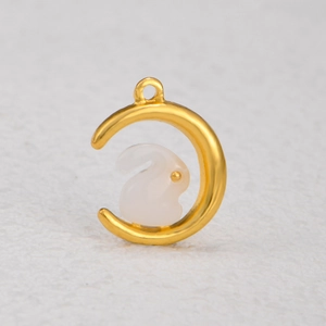 Vue macro d'un pendentif lune dorée et lapin en jade blanc pour bijoux DIY