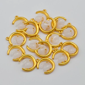 Gros plan de breloques lune dorée et lapin blanc pour la fabrication de bijoux DIY
