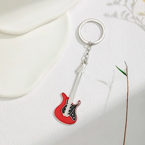 Detail of red electric guitar keychain with enamel finish and silver chain on white background