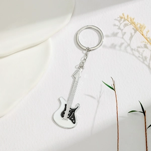 Detailed macro of white electric guitar keychain with black pickguard on white texture