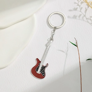 Macro detail of red guitar keychain with metallic silver pickups and black pickguard