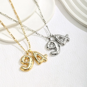 Detailed close-up of 94 number pendant necklaces in gold and silver with Figaro chain