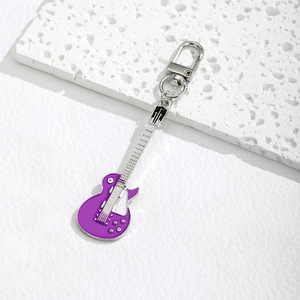 Creative purple electric guitar keychain with silver hardware on white stone background