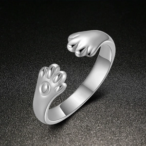 Nahaufnahme des silbernen Katzenpfoten-Rings mit feiner Metalltextur auf dunklem Grund