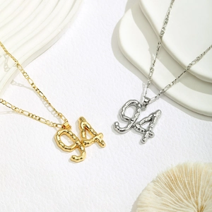 Detail of liquid metal texture gold and silver 94 number pendants on Figaro chains