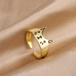 Nahaufnahme eines goldenen Katzenrings mit schwarzen Details auf Satinhintergrund