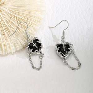 Détail de boucles d'oreilles gothiques avec cœurs noirs, croix et bordures d'épines
