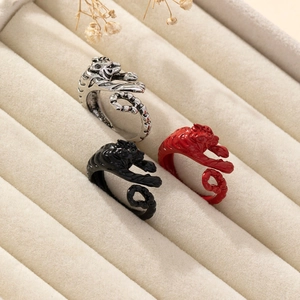 Three tiger dragon open rings in silver, black, and red set on a beige jewelry display