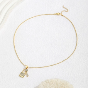 Detail van gouden kralenketting met hartslot en sleutelhangers bezet met glimmende strass