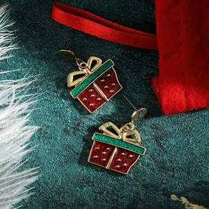 Detail von Weihnachtsgeschenkbox-Ohrringen mit Emaille auf dunkelgrünem Hintergrund