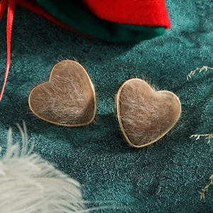 Macro di orecchini a cuore floccati marroni con cornice dorata in ambientazione festiva