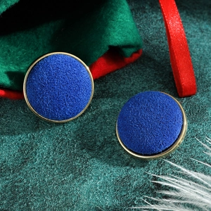 Macro shot of royal blue velvet round earrings with gold trim and festive decor