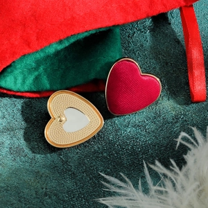 Dettaglio degli orecchini a cuore in velluto rosso con bordo dorato e retro in metallo