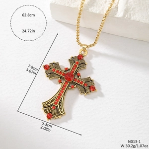 Vintage gold cross pendant necklace with red rhinestones and measurements on white wall