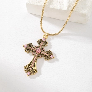 Detail of vintage punk cross pendant with pink rhinestones on a gold box chain