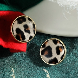 Close-up of golden round leopard print earrings on a festive red and green background