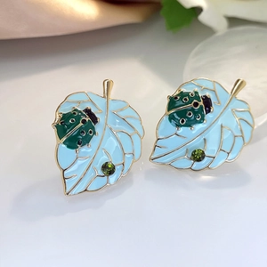 Emaille lieveheersbeestje op blauw blad oorbellen met groene strassteentjes en goud