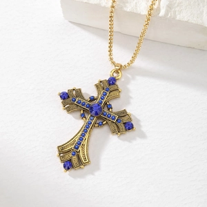 Macro detail of gothic cross pendant with deep blue rhinestones on a gold bead chain