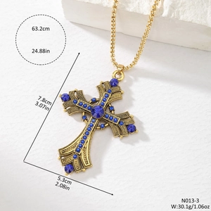 Detail of vintage gold cross pendant with blue rhinestones and hollow-out carving