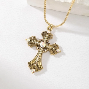 Macro shot of vintage gold cross necklace with multicolored rhinestones and intricate details