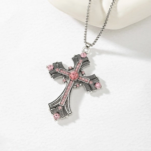 Detailed close-up of a vintage silver cross pendant with sparkling pink rhinestones