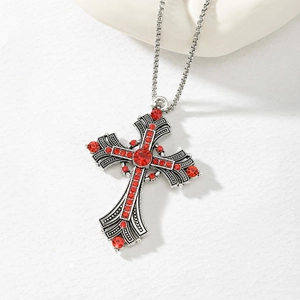 Macro view of silver gothic cross pendant with vintage texture and red rhinestones