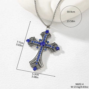 Macro detail of silver cross pendant with blue crystals and vintage embossed texture