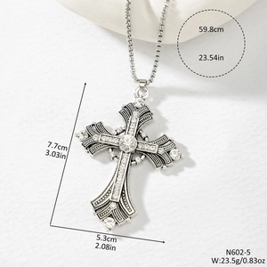 Detailed view of silver cross pendant with rhinestones measuring 7.7 by 5.3 centimeters