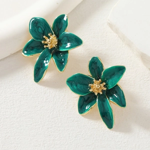 Vista macro de pendientes de flor en esmalte verde oscuro con bordes y detalles dorados