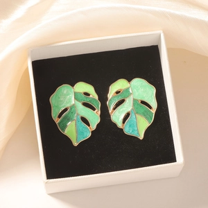 Macro-detail van Monstera-blad oorbellen met groen verloop emaille op goud metaal