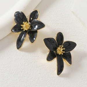 Detalle de los pendientes de flores en esmalte negro jaspeado con acabados metálicos dorados
