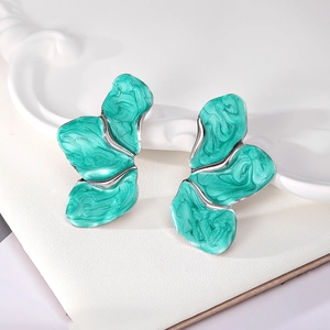 Macro shot of silver metal earrings with green marble enamel and petal wing design