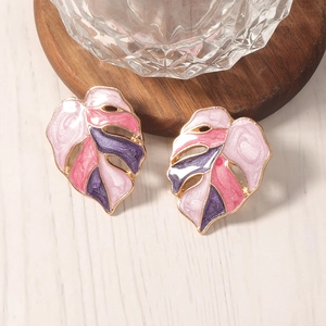 Detailopname van holle monstera blad oorbellen met roze en paars emaille afwerking
