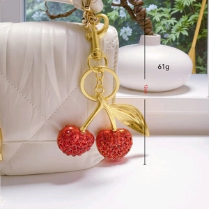 Sparkling crystal cherry keychain and bag charm in gold metal, length 12cm and weight 61g