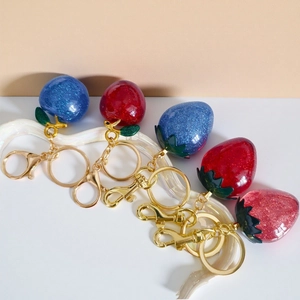 Detailed view of glittering resin fruit keychains with sparkling texture and gold lobster clasp